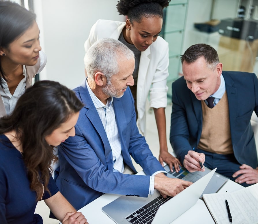 3 women and 2 men sitting around a laptop